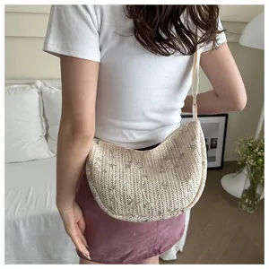 Detailed close-up of cream woven crossbody bag with floral embroidery and wide strap