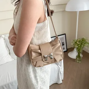 Beige pleated bow shoulder bag for women with silver metal buckle in a cozy home setting