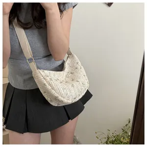 Detailed view of beige woven bag with floral embroidery and wide fabric strap