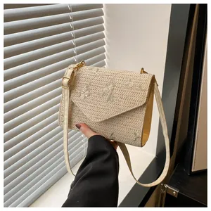 Close-up of cream woven straw bag with delicate floral embroidery and gold metal clasp