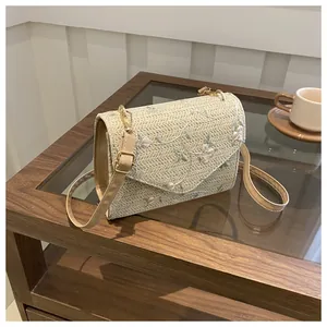 Detail of woven straw bag featuring elegant pink floral embroidery and a leather strap