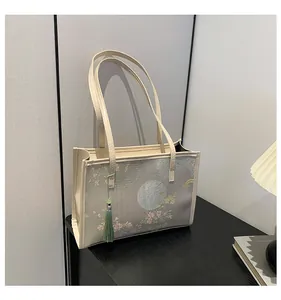 Dettaglio della borsa tote con stampa floreale e nappa con perle di giada su tavolo