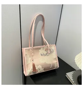 Dettaglio del ricamo floreale rosa e della nappa sulla elegante borsa a tracolla