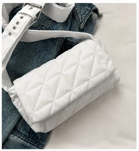 Close-up of white quilted crossbody bag featuring padded stitching and wide strap