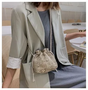 Détail du sac seau en paille tissée beige avec broderie florale et bandoulière corde