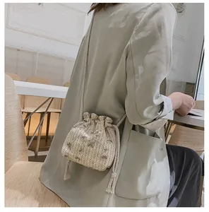 Détail de broderie de fleurs vertes sur sac seau en paille crème avec cordons à glands