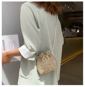Détail d'un mini sac seau tissé avec de délicates broderies florales roses et vertes