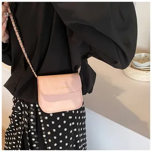 Detail of pink mini square crossbody bag with gold rich rabbit text and metal chain strap