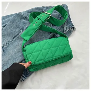 Detail of bright green quilted crossbody bag with adjustable wide eyelet strap on denim