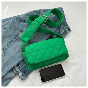 Detail of green quilted crossbody bag with wide adjustable strap and metal buckle