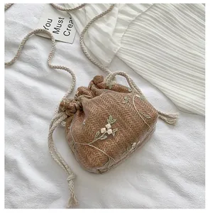 Détail de la broderie florale sur un sac seau à cordon en tissu à chevrons marron