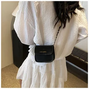 Detail of the golden chain strap and rich rabbit logo on a black leather crossbody bag