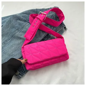Detail of pink quilted puff shoulder bag with adjustable eyelet strap on denim jacket