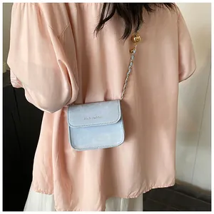 Close-up of light blue mini chain bag with gold ball decor and rich rabbit lettering