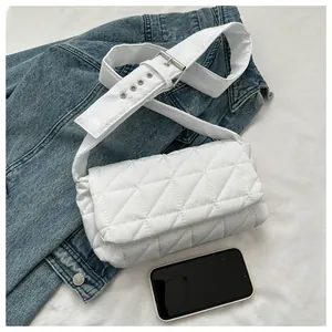 Detailed close-up of white quilted crossbody bag with adjustable wide fabric strap