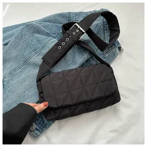 Close-up of black quilted puffer crossbody bag with adjustable silver buckle strap