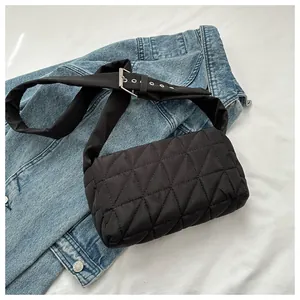 Close-up of black quilted oxford fabric and silver metal buckle on crossbody bag