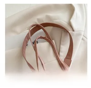 Vue détaillée des doubles bandoulières confortables d'un sac seau en cuir rose-marron