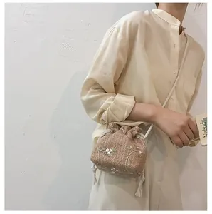 Détail du sac seau en paille tressée avec broderie florale et cordon de serrage blanc