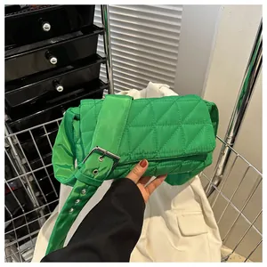 Close-up of bright green quilted nylon crossbody bag with wide strap and silver buckle