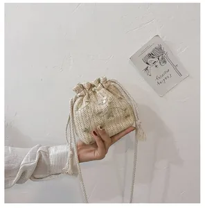 Détail du sac seau tissé main avec broderie de fleurs vertes et cordon de serrage en coton