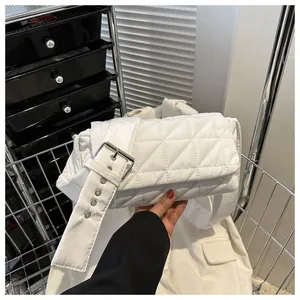 Detail of white quilted nylon bag featuring a wide strap and large silver metal buckle