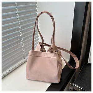 Détail d'un sac seau en daim rose avec de longues anses et un fermoir métallique