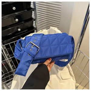 Close-up of klein blue quilted crossbody bag with stylish diamond pattern and belt detail