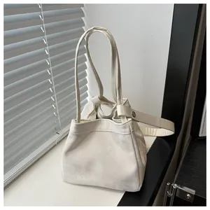 Détail du sac seau minimaliste blanc crème avec cordon de serrage sous une lumière naturelle