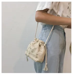 Détail du sac seau en paille tissé à la main avec broderie florale verte et cordon