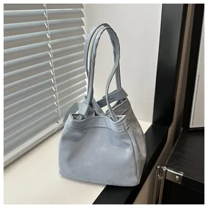 Détail du sac seau bleu clair à cordon avec bouton pression et texture mate douce