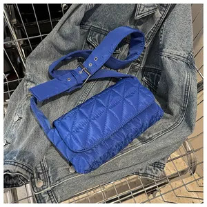 Close-up of Klein blue quilted crossbody bag with wide shoulder strap and silver buckle