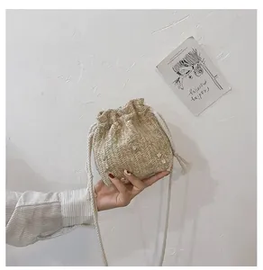 Détail du sac seau en paille tissé à la main avec broderie florale et fermeture par cordon