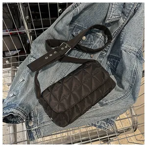 Quilted black nylon crossbody bag with silver hardware on casual denim background