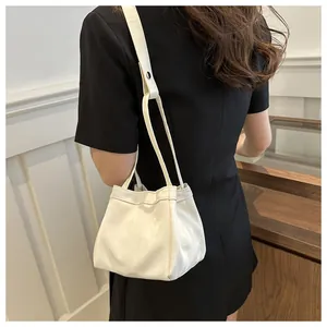 Vue détaillée d'un sac seau blanc à cordon porté sur une robe noire élégante