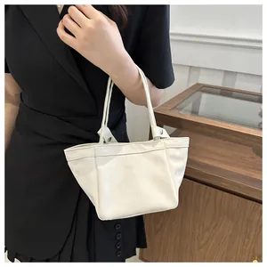 Détail du sac seau blanc crème minimaliste avec texture cuir et rivets métalliques argentés