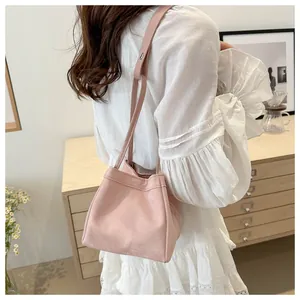 Détail du sac seau rose clair en daim avec cordon de serrage porté par un mannequin
