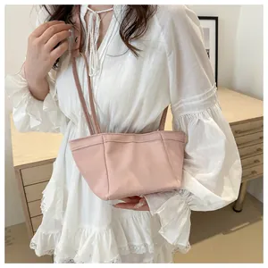 Détail d'un sac seau rose clair à cordon avec fine bandoulière porté par un mannequin