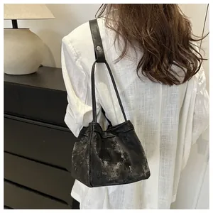Gros plan du sac seau vintage noir avec texture argentée vieillie et fines lanières en cuir