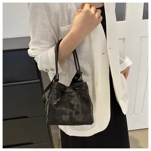 Détail du sac seau gris foncé avec texture vintage et fines anses noires