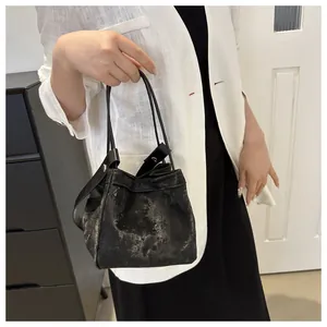 Sac seau noir chic à texture métallique présenté sur un mannequin au style épuré