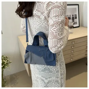 Détail du sac bandoulière asymétrique en patchwork de denim avec coutures jaunes