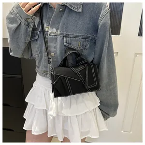 Détail d'un mini sac en toile noire avec surpiqûres blanches et une poignée nouée