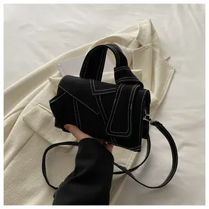 Détail du sac à bandoulière noir avec surpiqûres contrastées blanches et boucles argent