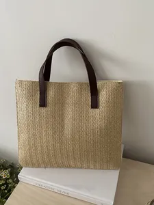 Detailed view of the herringbone straw weave and premium leather handles on the tote bag