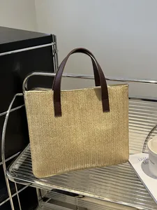 Detail of woven straw tote bag texture with brown leather handle on a metal shelf