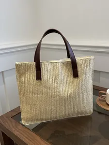 Detail of straw woven tote bag featuring brown leather handles and V-shaped texture