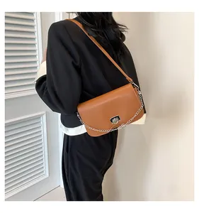 Détail du sac bandoulière marron avec fermoir anneau argenté sur un mannequin en tailleur