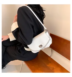 Détail d'un sac à bandoulière en cuir blanc avec boucle argentée et chaîne décorative