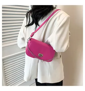 Détail du sac bandoulière rose rouge avec fermoir rotatif argenté porté par un mannequin